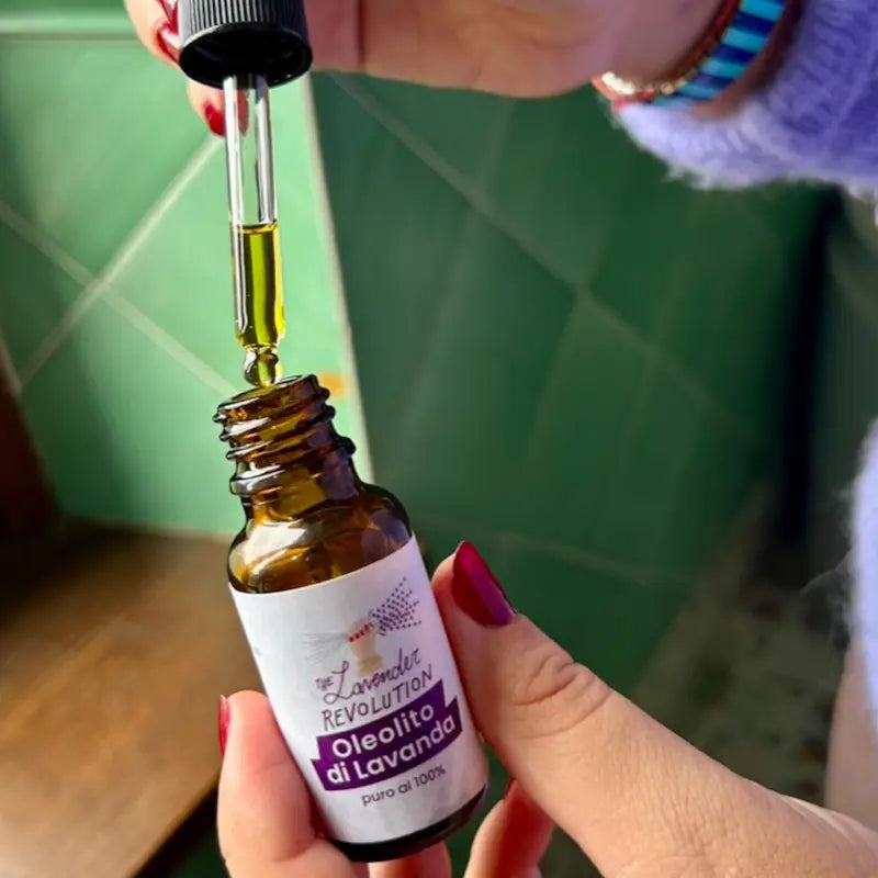 Pipetta dell'Oleolito di Lavanda con goccia d'olio dorato in primo piano, dettaglio della texture